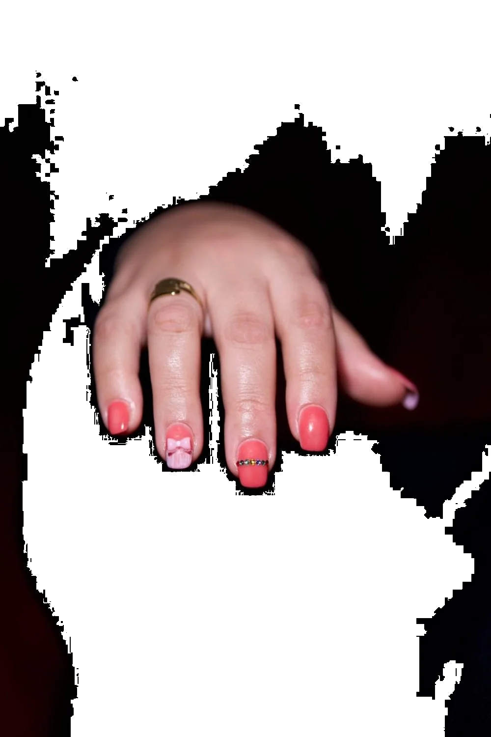 coral pink nails with a gradient design and gold accents on a hand against a dark background