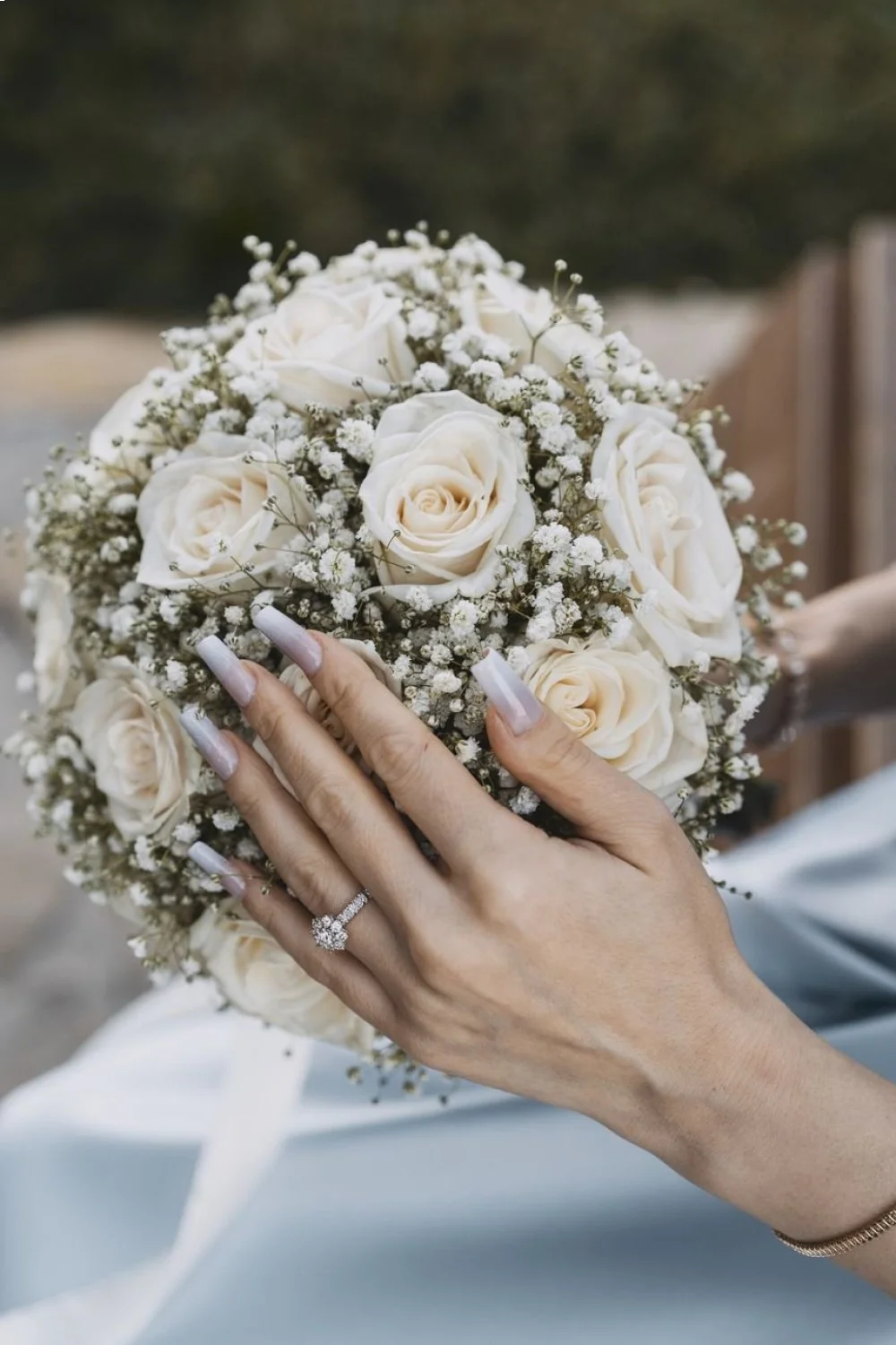Oval baby blue acrylic nails with white cloud details against a clear summer sky background showcasing summer acrylic nails