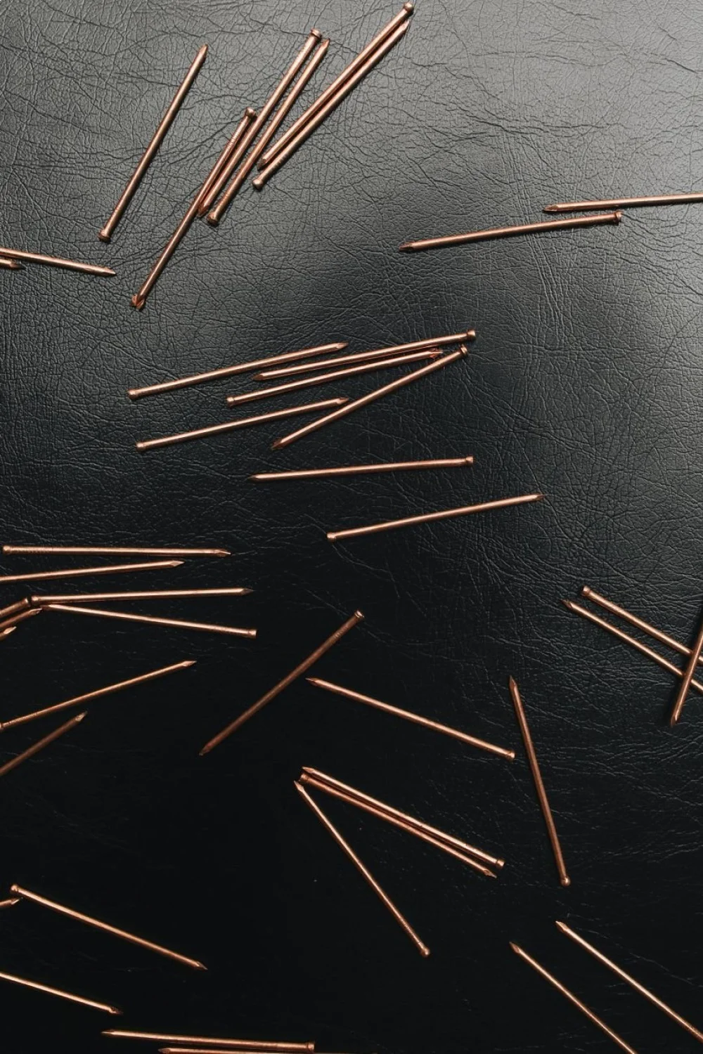 copper nail forms scattered on a black surface for summer acrylic nails preparation